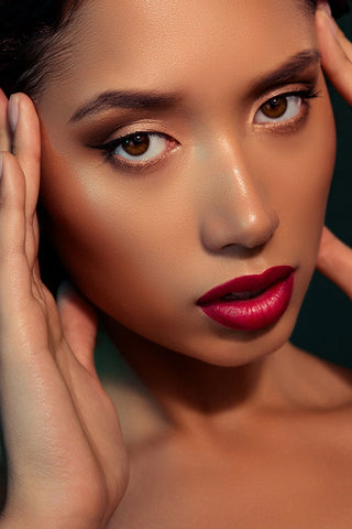 Model with flawless glowing skin wearing bold fuchsia lipstick, soft glam eye makeup, and winged liner, showcasing Mirabella’s new lip shade.