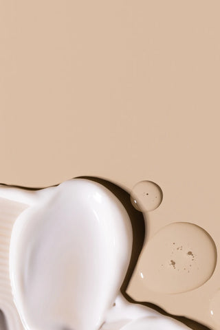 Close-up of creamy skincare texture with beige background, representing Mirabella Clarifying Serum and Hydrate • Prime • Protect SPF 30 Primer.