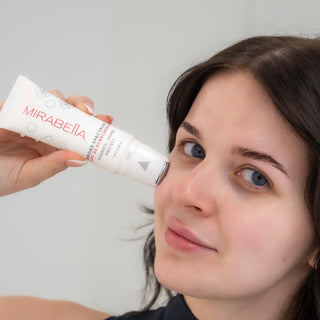 Woman applying Mirabella Hydrate • Prime • Protect Broad Spectrum SPF 30 face primer during a summer skincare routine.