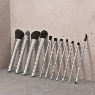 Mirabella professional makeup brushes arranged in a row, showcasing face and eye brush shapes with sleek silver handles against a neutral background.