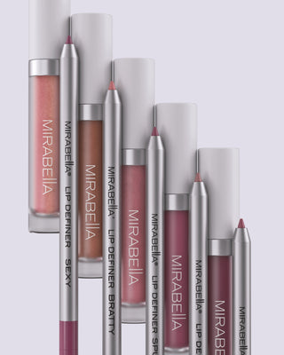 Mirabella Beauty lip collection featuring Luxe Advanced Formula Lip Gloss tubes and Lip Definer pencils in various shades.