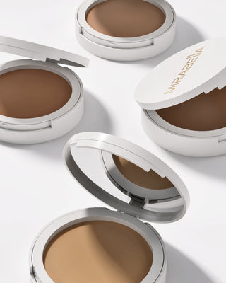 Mirabella Pure Press Powder compacts in multiple shades with sleek white packaging, showcasing inclusive pressed powder foundation for flawless skin.
