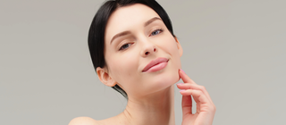 Woman with smooth, radiant skin and natural makeup, gently touching her face, highlighting hydrated, youthful-looking skin with Mirabella Renew Age-Defying Daily Moisturizer.