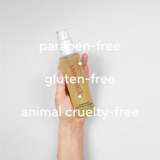 Hand holding Mirabella Skinphony Pro Face Cleanser against neutral background with overlay text paraben free gluten free and animal cruelty free.