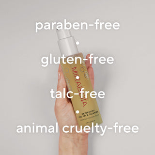 Hand holding Mirabella Skinphony Pro Face Cleanser bottle against a soft neutral background with overlay text highlighting paraben-free, gluten-free, talc-free, and animal cruelty-free formula.