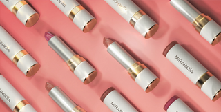 Close-up of Mirabella Soft Satin lipstick bullets in soft shimmer pink and nude shades with clean gold and white packaging.