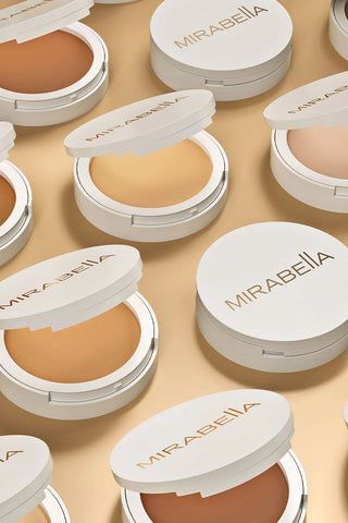 Flat lay of Mirabella Pure Press powder compacts in multiple shades, showcasing buildable mineral foundation.