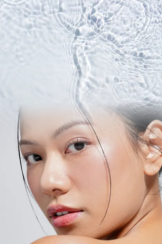 Close-up of woman with glowing, radiant skin against a water ripple background highlighting Mirabella Clarifying Serum and SPF 30 Primer.