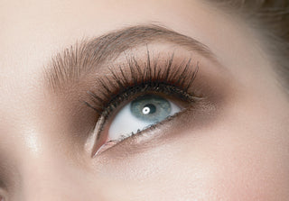 Close-up of closed eyes showcasing soft neutral eye makeup and naturally defined lashes.