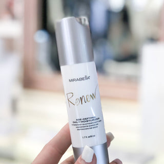 Image of Mirabella Beauty's Renew Age Defying Daily Moisturizer for the face being held up.